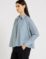 Profil de la Chemise évasée à rayures bleu indigo pour femme, modèle Grace de la marque Hana San. Présente une patte de boutonnage cachée, une emmanchure marteau et de longues pattes poignets boutonnées.