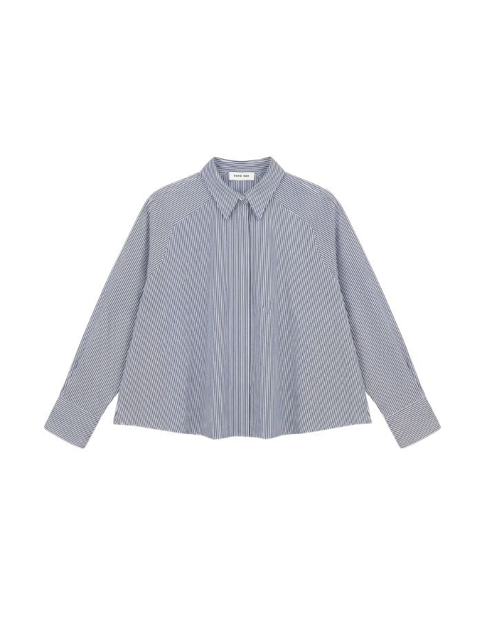 Chemise évasée à rayures bleu indigo pour femme, modèle Grace de la marque Hana San. Présente une patte de boutonnage cachée, une emmanchure marteau et de longues pattes poignets boutonnées.