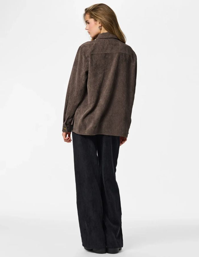 Silhouette de dos avec la Chemise ample pour femme en velours côtelé à manches longues, modèle Effi de la marque Pieces. Tissu corduroy de couleur marron foncé chocolat Hot Fudge, avec des poches de poitrine boutonnées et des poignets élastiqués.