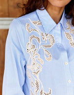 Col du Chemisier droit pour femme à rayures écru et bleu, modèle Clema de la marque LA PETITE ÉTOILE. Présente un col chemise et une grande broderie ajourée asymétrique sur le devant.