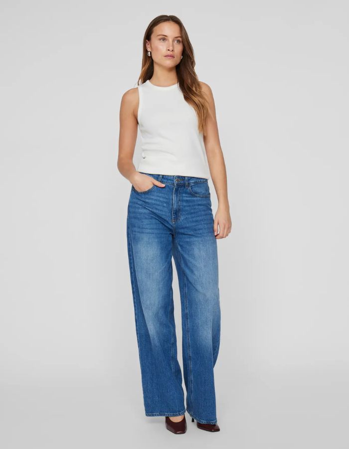 Débardeur blanc côtelé en coton biologique Sola Vila, coupe ajustée, porté avec un jean bleu.