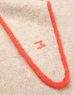 Détail du logo sur l'Écharpe triangle pour femme en baby alpaga doux avec liseré contrastant orange pepsy, modèle Écharpe Elly N°218 Cord Clown de la marque MOISMONT.
