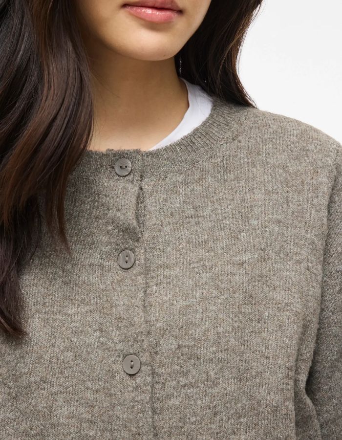 Col du Gilet fin en maille pour femme de couleur taupe grisâtre chiné Falcon Melange, modèle Liga de la marque Vila. Présente un col rond, une fermeture par petits boutons sur le devant et des manches mi-longues arrivant juste en dessous du coude.