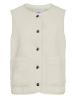 Gilet sans manches pour femme en matière peluche bouclée de couleur beige clair, modèle Ada de la marque Vila. Présente un col rond, une fermeture boutonnée à l'avant et deux poches plaquées.