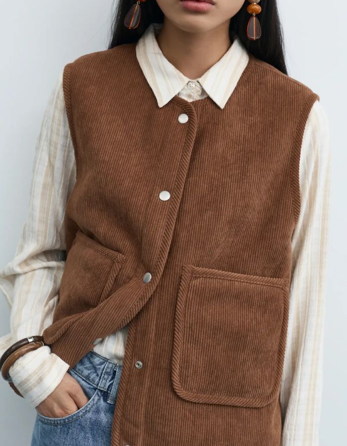 Col du Gilet sans manches réversible pour femme, modèle Majlina Teddy Vest de la marque VILA. Présente une face en moumoute écru Birch et une face en velours côtelé marron Nuthatch, avec col rond, boutons et poches sur l'avant.
