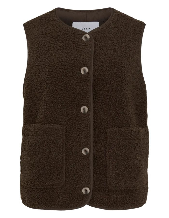 Gilet sans manches pour femme en matière peluche bouclée marron foncé Coffee Bean, modèle Ada de la marque Vila. Présente un col rond, une fermeture boutonnée à l'avant et deux poches plaquées.