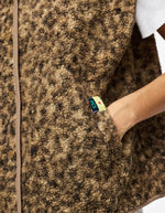 Poche du Gilet sans manches Katty Teddy pour femme avec imprimé léopard tacheté. Texture polaire bouclée douce, col en V et poches sur les côtés. Veste sans manches tendance en polyester recyclé.
