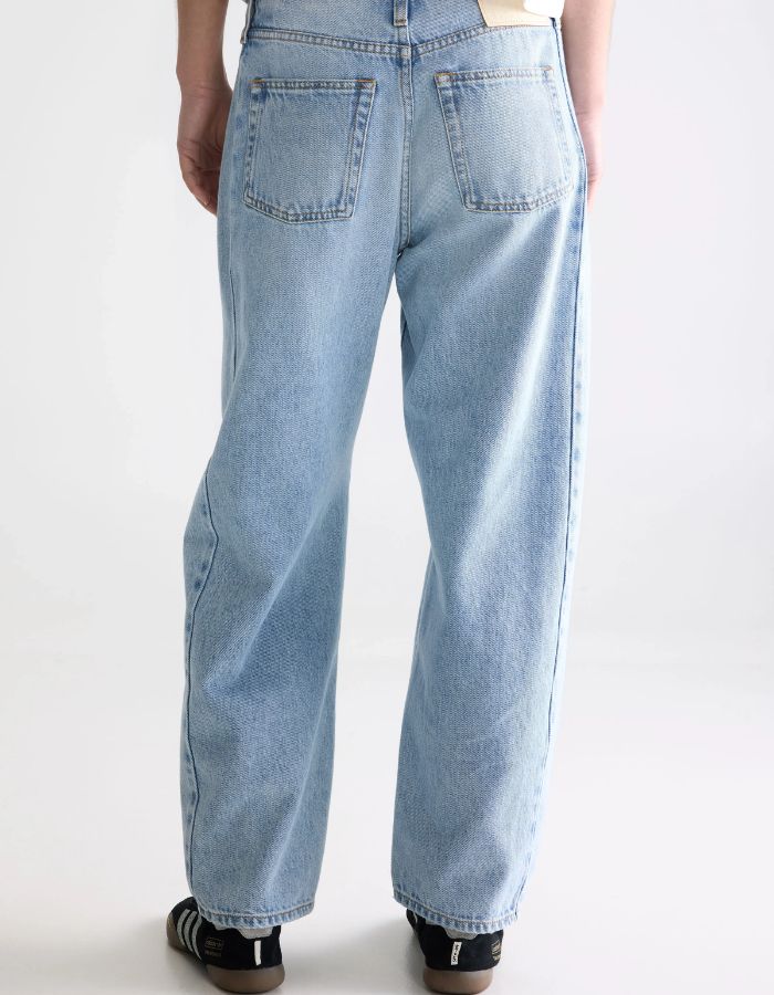 Jean Pacy N°55 loose en denim bleu clair effet bleach, taille basse, jambes larges et coutures apparentes.