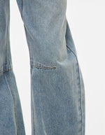 Détail de la jambe du Jean pour femme de couleur bleu clair délavé Light Blue Denim, modèle Tiana de la marque Rouge Edit. Présente une coupe droite ample contemporaine, une taille mi-haute avec des passants de ceinture et des finitions de boutons en métal doré mat Dull Gold.