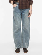 Silhouette avec le Jean pour femme de couleur bleu clair délavé Light Blue Denim, modèle Tiana de la marque Rouge Edit. Présente une coupe droite ample contemporaine, une taille mi-haute avec des passants de ceinture et des finitions de boutons en métal doré mat Dull Gold.