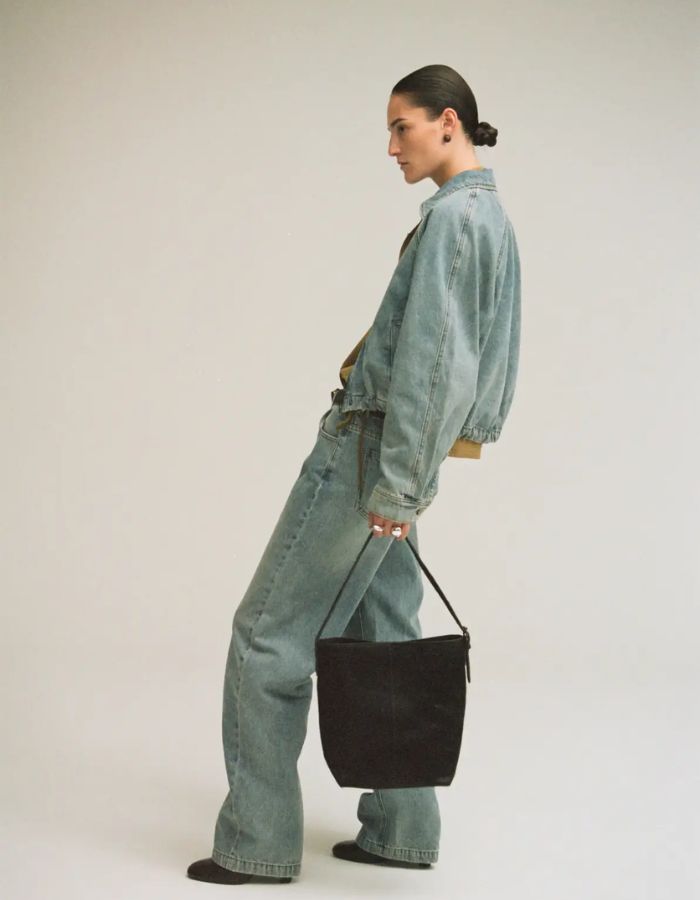 Total look avec le Jean pour femme de couleur bleu clair délavé Light Blue Denim, modèle Tiana de la marque Rouge Edit. Présente une coupe droite ample contemporaine, une taille mi-haute avec des passants de ceinture et des finitions de boutons en métal doré mat Dull Gold.