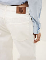 Jean flare Badou écru en coton biologique, taille basse, avec patch logo en cuir marron au dos.