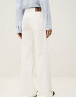 Jean flare Badou écru en coton biologique, taille basse, coupe large avec empiècement latéral et étiquette en cuir.