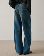 Jean Gaspard bleu/vert ample en coton biologique et recyclé avec pinces aux genoux et patch en cuir.