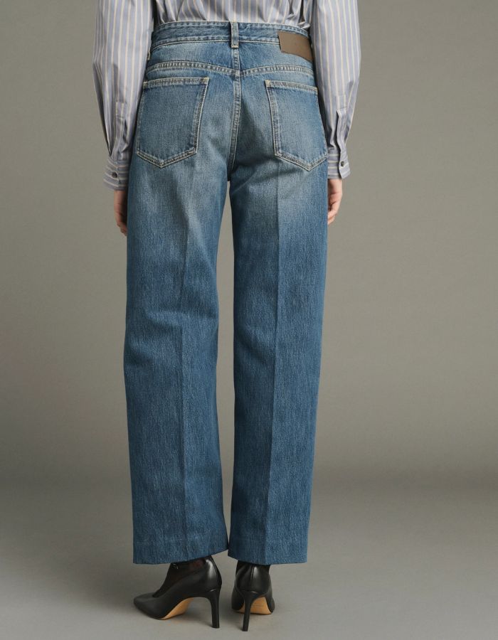 Dos du Jean droit pour femme en denim bleu délavé avec plis marqués devant et dos, modèle Jerry de la marque SOEUR. Présente une coupe droite 5 poches, une fermeture boutonnée zippée et un patch en cuir au dos.