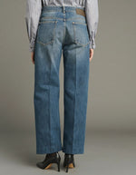 Dos du Jean droit pour femme en denim bleu délavé avec plis marqués devant et dos, modèle Jerry de la marque SOEUR. Présente une coupe droite 5 poches, une fermeture boutonnée zippée et un patch en cuir au dos.