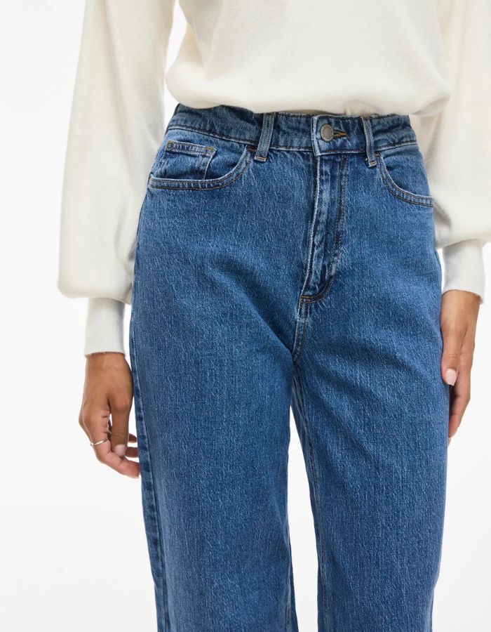 Bassin avec le Jean large pour femme de couleur bleu moyen Medium Blue Denim, modèle Reya de la marque Vila. Présente une taille haute ajustée et des jambes amples fluides (coupe Frida), avec une fermeture par zip.