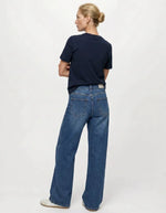 Silhouette de dos avec le Jean large pour femme de couleur bleu moyen délavé Medium Blue Denim, modèle Rio Mae de la marque OBJECT. Présente une taille mi-haute, des jambes larges amples, une fermeture à bouton et zip et un style cinq poches classique.