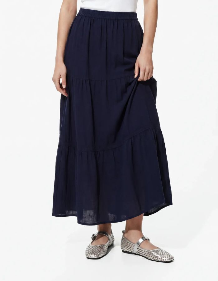Vue de face de la Jupe longue taille haute Tohime par Pieces de couleur bleu marine (Maritime Blue). Coupe fluide longueur cheville en pur coton avec de délicates bandes de dentelle horizontales.