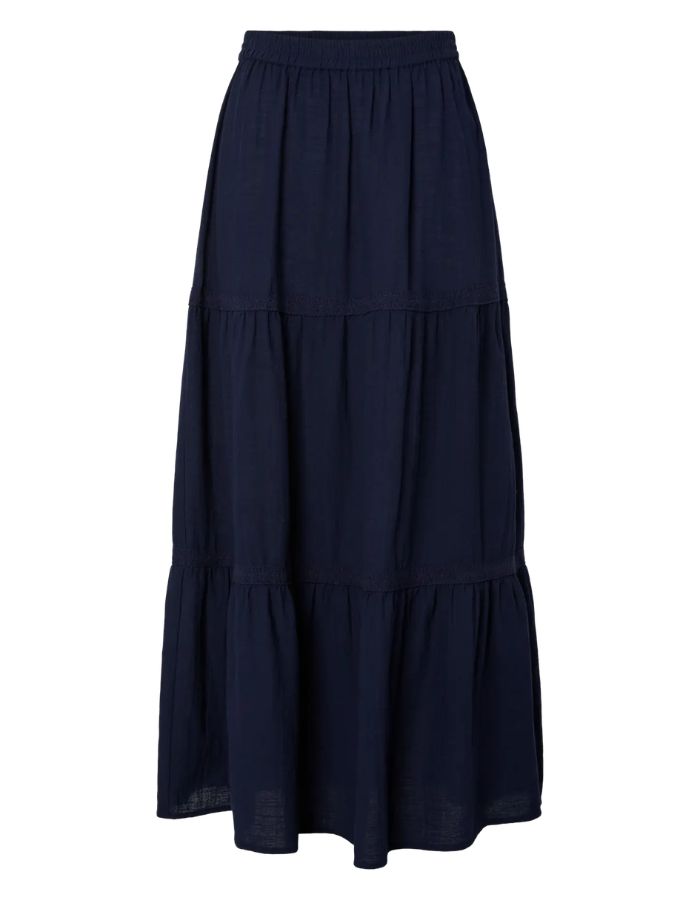 Jupe longue taille haute Tohime par Pieces de couleur bleu marine (Maritime Blue). Coupe fluide longueur cheville en pur coton avec de délicates bandes de dentelle horizontales.