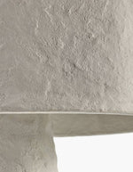Gros plan sur la texture minérale et irrégulière d'un lampadaire Earth en papier mâché blanc.
