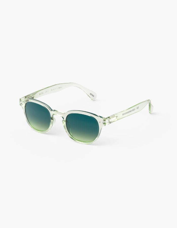 Côté des Lunettes de soleil unisexes IZIPIZI modèle #C de forme carrée vintage épaisse. La monture brillante est d'un coloris vert doux et légèrement translucide nommé Green Fields, associée à des verres solaires polarisés protecteurs