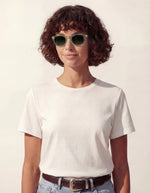 Femme avec les Lunettes de soleil unisexes IZIPIZI modèle #C de forme carrée vintage épaisse. La monture brillante est d'un coloris vert doux et légèrement translucide nommé Green Fields, associée à des verres solaires polarisés protecteurs