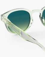 Verre des Lunettes de soleil unisexes IZIPIZI modèle #C de forme carrée vintage épaisse. La monture brillante est d'un coloris vert doux et légèrement translucide nommé Green Fields, associée à des verres solaires polarisés protecteurs