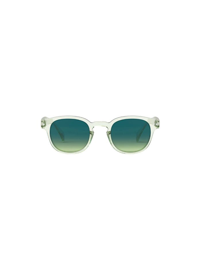 Lunettes de soleil unisexes IZIPIZI modèle #C de forme carrée vintage épaisse. La monture brillante est d'un coloris vert doux et légèrement translucide nommé Green Fields, associée à des verres solaires polarisés protecteurs