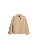 Manteau court pour femme en laine double face beige chiné, modèle Windsor de la marque SOEUR. Présente une coupe ample au volume rond, un col asymétrique, une patte de boutonnage semi-cachée et deux grandes poches plaquées sur le devant.
