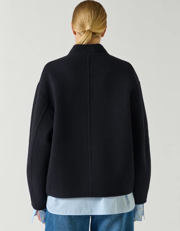 Dos du Manteau court pour femme en laine double face bleu marine profond Deep Navy, modèle Windsor de la marque SOEUR. Présente une coupe ample au volume rond, un col asymétrique, une patte de boutonnage semi-cachée et deux grandes poches plaquées sur le devant.