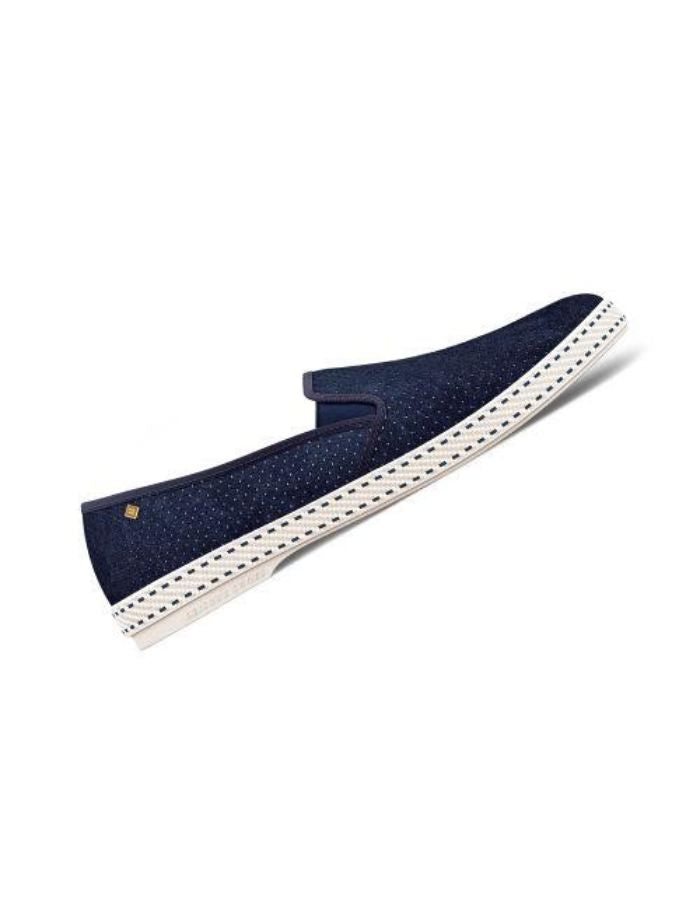 Profil des Mocassins Rivieras Classic en daim bleu marine perforé. Semelle blanche contrastée avec couture selle en coton, élastiques de confort et rivet métallique logoté sur le côté. Design intemporel fabriqué en Espagne.