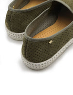 Vue sur le talon des Mocassins Rivieras Classic Suede en cuir perforé kaki. Détail de biais en gros-grain, semelle blanche avec couture selle en coton et rivet logo métallique. Design élégant fabriqué en Espagne.
