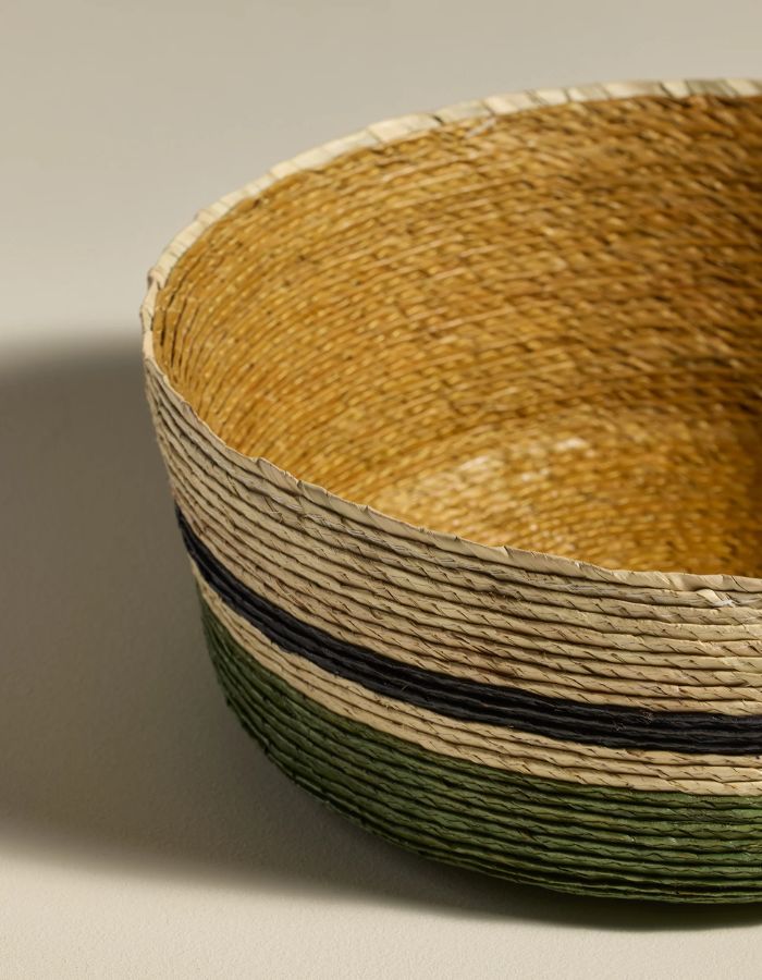 Détail du Grand panier rond Globe par Maison Sarah Lavoine. Tressage artisanal en fibres de palmier avec rayures horizontales coloris Eucalyptus et Ocre, fabriqué au Mexique, dimensions H9 x Ø25 cm.