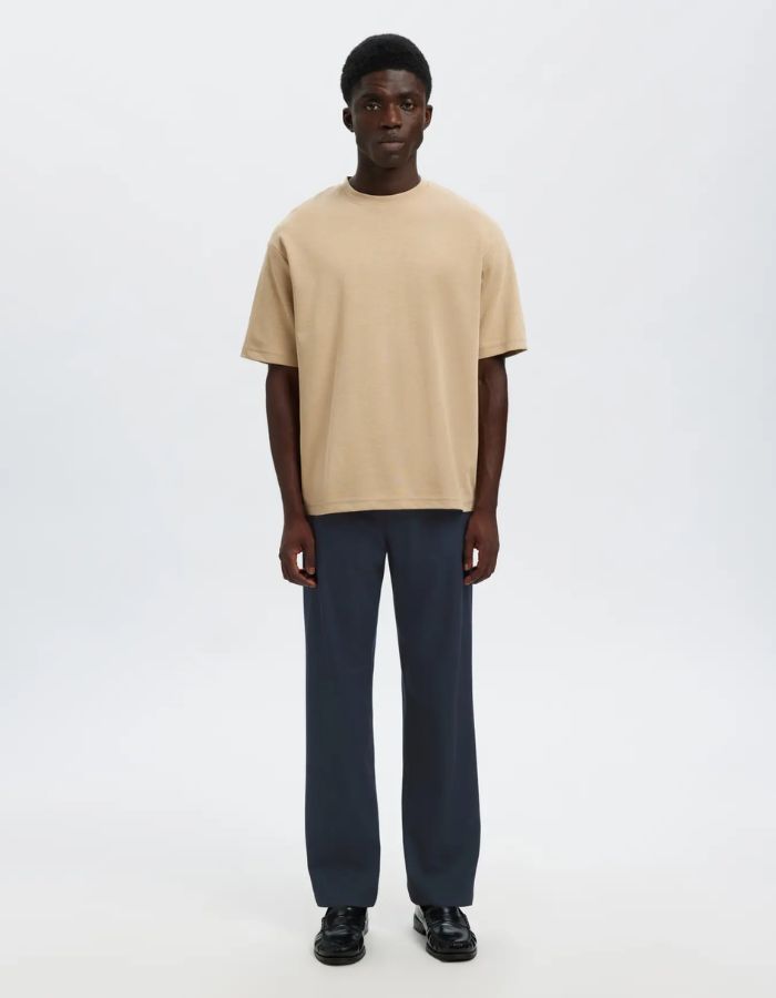 Silhouette avec le Pantalon droit pour homme de couleur bleu marine foncé Dark Sapphire, modèle Straight Robert String Pant de la marque Selected. Présente une coupe droite contemporaine, des poches latérales, et une ceinture hybride élastiquée ajustable à l'aide d'un cordon de serrage noir et d'une fermeture par bouton.
