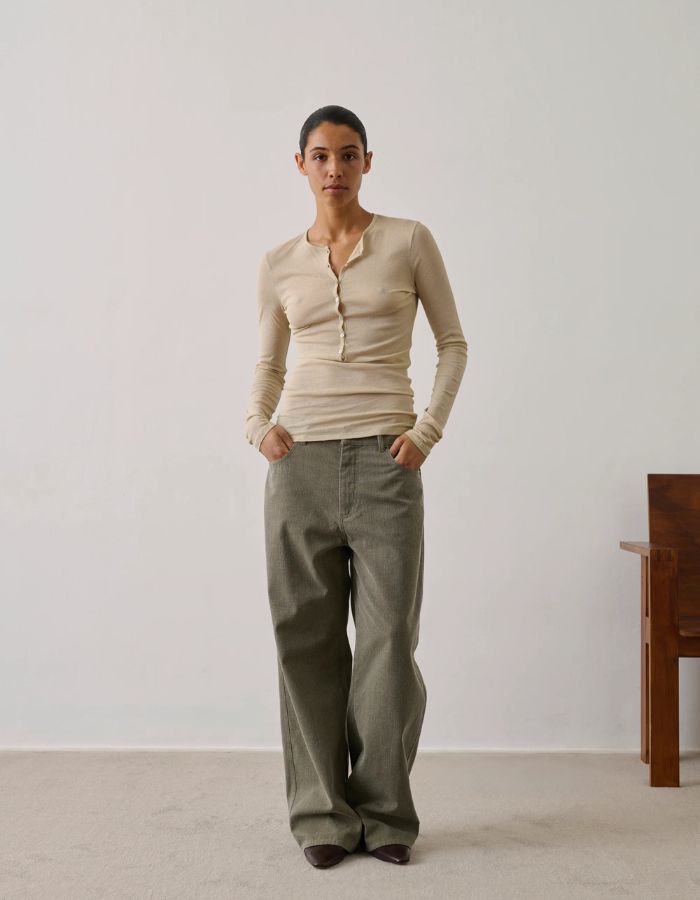 Femme portant un pantalon Hunter kaki oversize en canvas de coton biologique avec un haut beige.