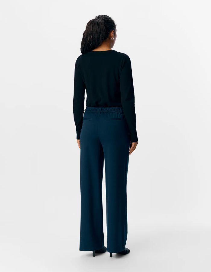 Dos du Pantalon large pour femme de couleur bleu marine foncé Sky Captain, modèle Lisa Wide Pant de la marque Object. Présente une coupe droite très ample de style wide-leg, une taille mi-haute froncée par un élastique confortable et des poches discrètes insérées dans les coutures latérales.