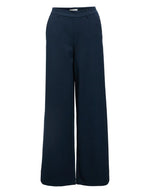 Pantalon large pour femme de couleur bleu marine foncé Sky Captain, modèle Lisa Wide Pant de la marque Object. Présente une coupe droite très ample de style wide-leg, une taille mi-haute froncée par un élastique confortable et des poches discrètes insérées dans les coutures latérales.