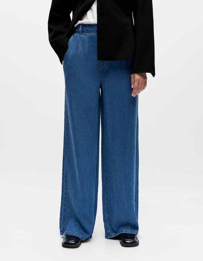 Pantalon large fluide denim bleu en lyocell TENCEL™ avec taille mi-haute et poches latérales.