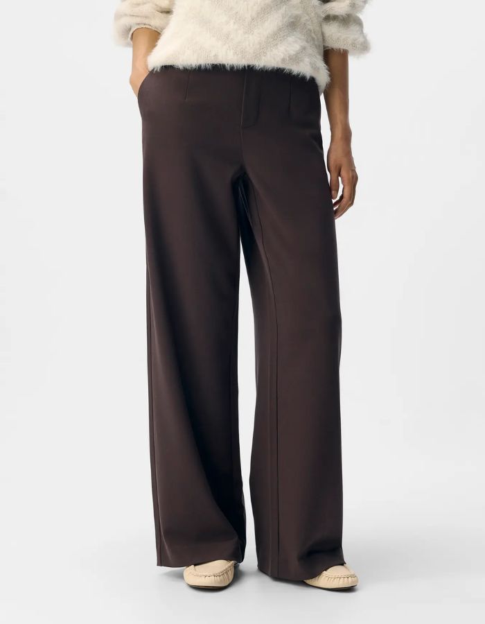 Vue de face du Pantalon large pour femme de couleur marron foncé chocolat Seal Brown, modèle Lisa Wide Pant de la marque Object. Présente une coupe droite très ample de style wide-leg, une taille mi-haute froncée par un élastique confortable et des poches discrètes insérées dans les coutures latérales.
