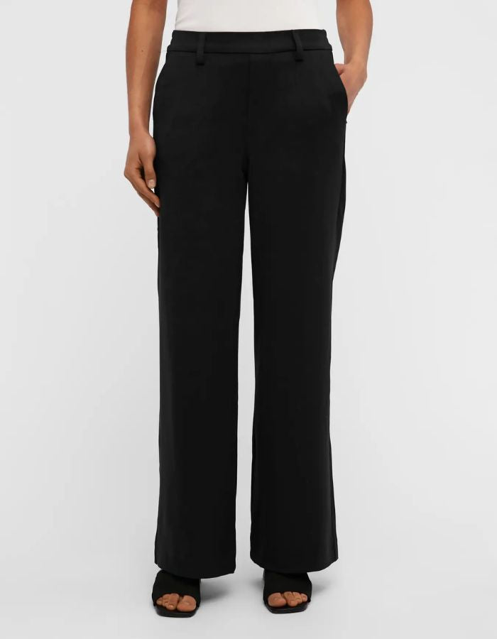 Devant du Pantalon large pour femme de couleur noir uni opaque, modèle Lisa Wide Pant de la marque Object. Présente une coupe droite très ample de style wide-leg, une taille mi-haute froncée par un élastique confortable et des poches discrètes insérées dans les coutures latérales.