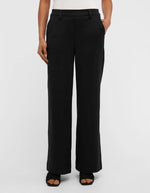 Devant du Pantalon large pour femme de couleur noir uni opaque, modèle Lisa Wide Pant de la marque Object. Présente une coupe droite très ample de style wide-leg, une taille mi-haute froncée par un élastique confortable et des poches discrètes insérées dans les coutures latérales.