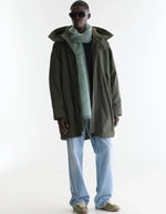 Vue de face de la Parka longue oversize pour homme couleur vert olive foncé avec capuche, fermeture zippée sous pression et poches en biais, modèle Jinx de la marque Bellerose.
