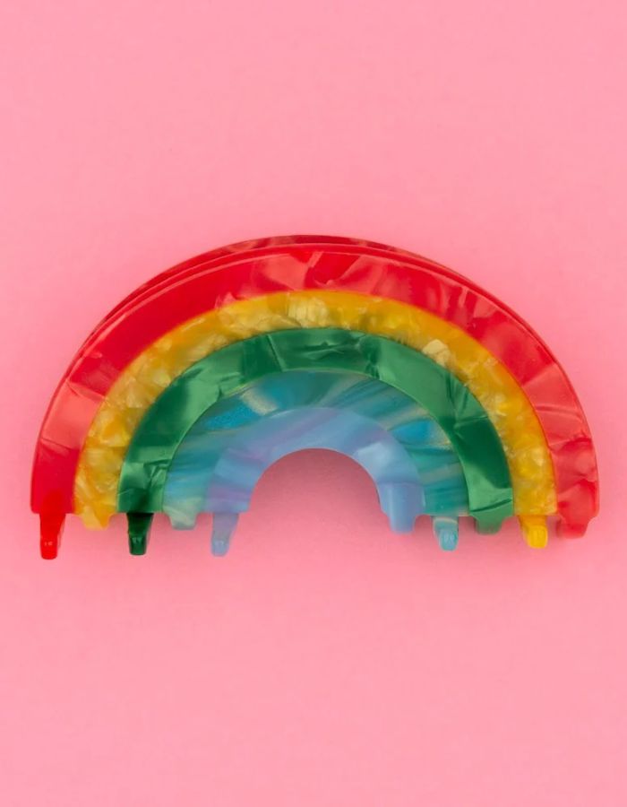 Pince à cheveux crabe de taille moyenne de la marque Coucou Suzette en acétate de cellulose brillant. L'accessoire prend la forme d'un arc-en-ciel incurvé aux bandes colorées et nacrées dans les tons rouge, jaune, vert, bleu et violet.