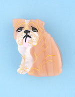 Petite pince à cheveux crabe de la marque Coucou Suzette en acétate de cellulose brillant. L'accessoire représente un chien bouledogue anglais marron et blanc de profil avec de jolis bourrelets, des petits yeux noirs et une petite langue rose pendante.