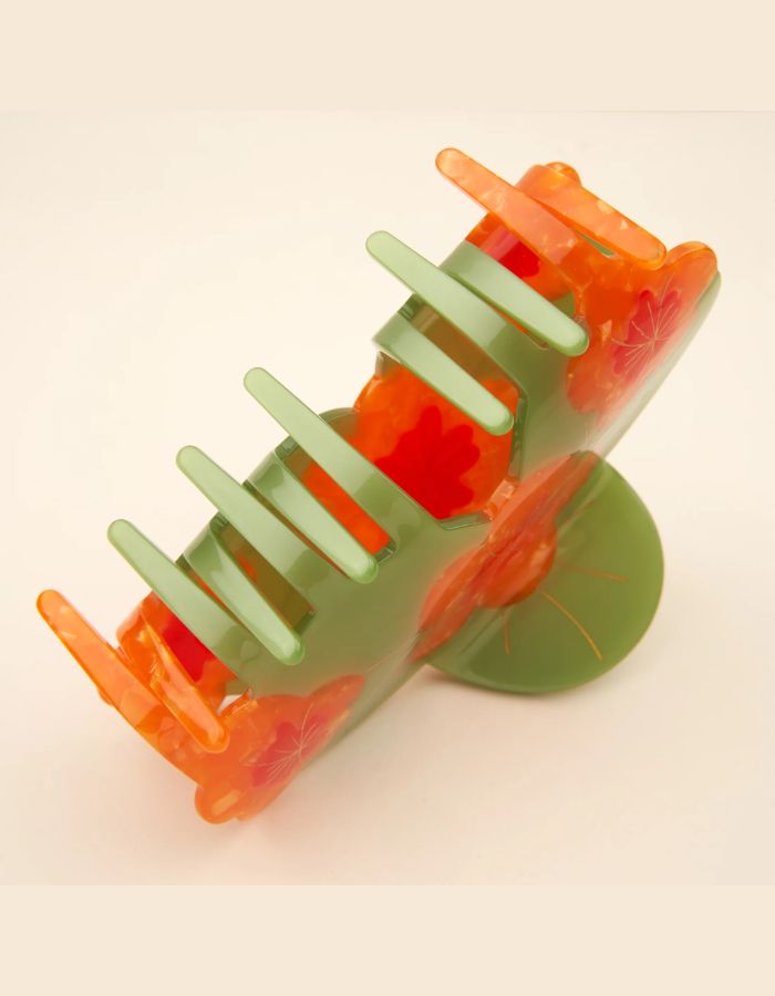Détail de la Grande pince à cheveux XL de la marque Coucou Suzette en acétate de cellulose brillant. L'accessoire est décoré de trois fleurs de capucines orange vif aux détails jaunes et feuilles vertes, idéale pour les cheveux épais.