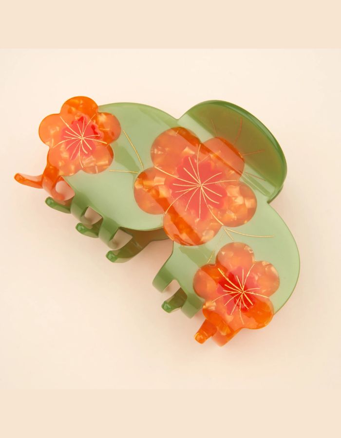 Grande pince à cheveux XL de la marque Coucou Suzette en acétate de cellulose brillant. L'accessoire est décoré de trois fleurs de capucines orange vif aux détails jaunes et feuilles vertes, idéale pour les cheveux épais.