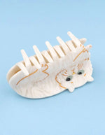 Gros plan sur la Pince à cheveux crabe de taille moyenne de la marque Coucou Suzette en acétate de cellulose couleur crème marbré. L'accessoire représente un chat persan frangé au visage boudeur avec de grands yeux bleus clairs.