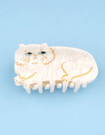 Pince à cheveux crabe de taille moyenne de la marque Coucou Suzette en acétate de cellulose couleur crème marbré. L'accessoire représente un chat persan frangé au visage boudeur avec de grands yeux bleus clairs.
