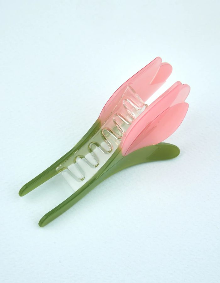 Détail de la Pince à cheveux crabe de la marque Coucou Suzette en acétate de cellulose brillant. L'accessoire prend la forme d'une tulipe graphique de couleur rose avec des feuilles vert tendre.